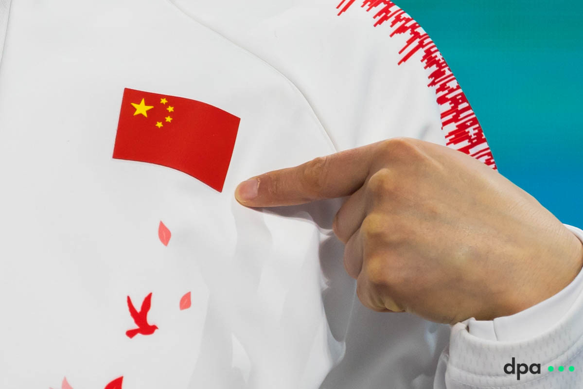 Sitong Liu of China points at the Chinese flag during the medal ceremony.