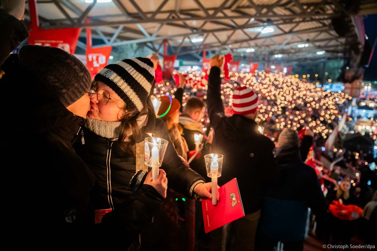 Katharina (centre) and Yvonne (left) kiss during the Christmas carol singing at the 1. FC Union stadium Alte Försterei.